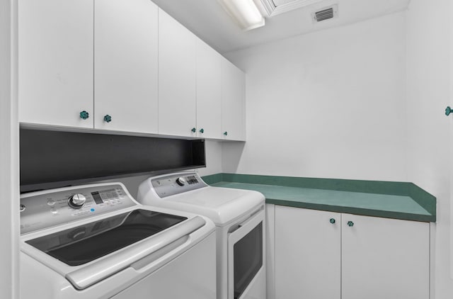 clothes washing area with cabinets and separate washer and dryer