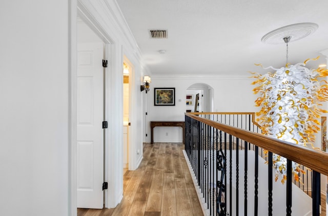 corridor with light wood-type flooring and crown molding