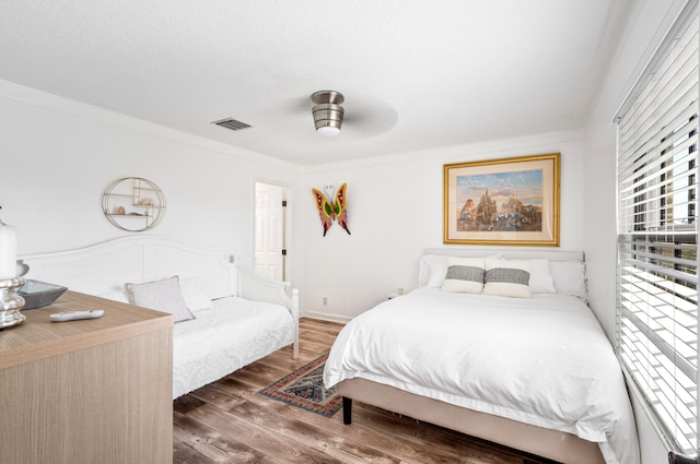 bedroom with dark hardwood / wood-style flooring, ornamental molding, and ceiling fan