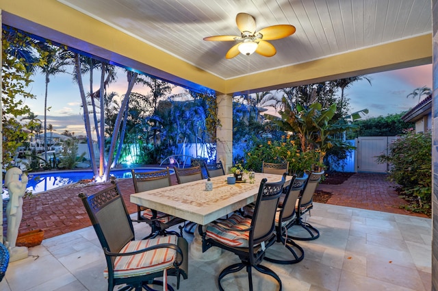 patio terrace at dusk featuring ceiling fan and a fenced in pool