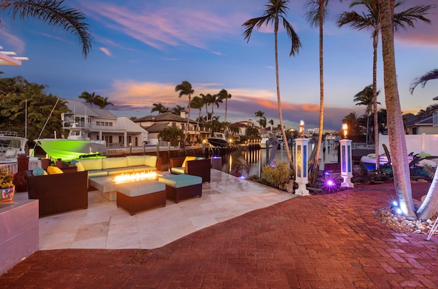 patio terrace at dusk with a water view and an outdoor living space with a fire pit