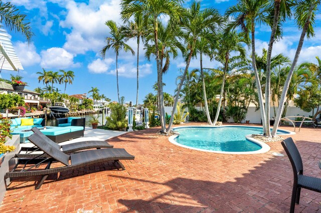 pool at dusk with a jacuzzi, a patio, pool water feature, and a water view