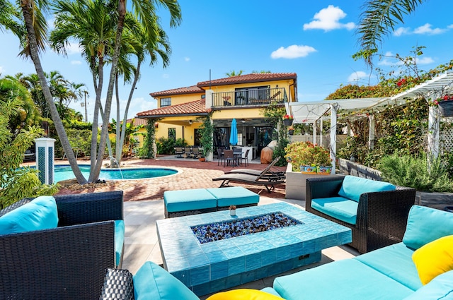 back of house with ceiling fan, a patio, a balcony, a pergola, and an outdoor living space with a fire pit