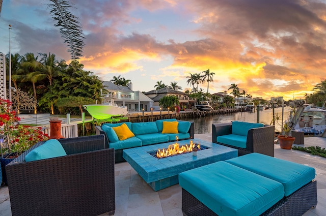 patio terrace at dusk featuring a water view and an outdoor living space with a fire pit