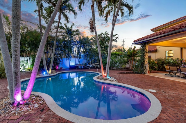 pool at dusk with a patio area