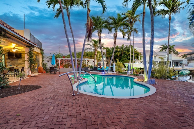 pool at dusk with an outdoor bar and a patio area