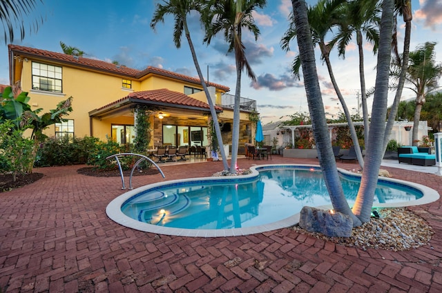 pool at dusk featuring a patio area