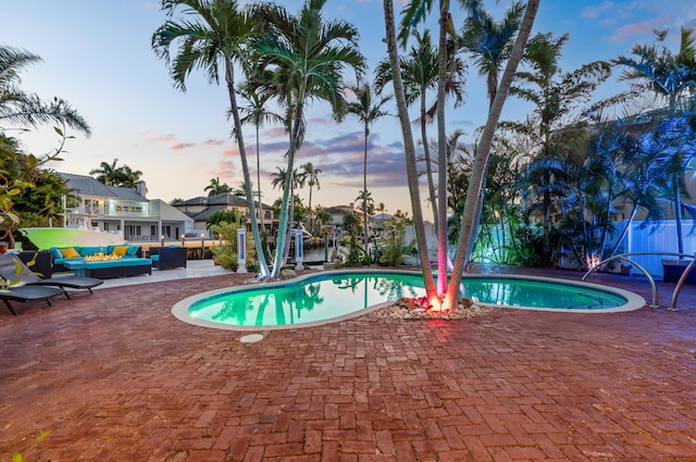 pool at dusk featuring a patio and outdoor lounge area