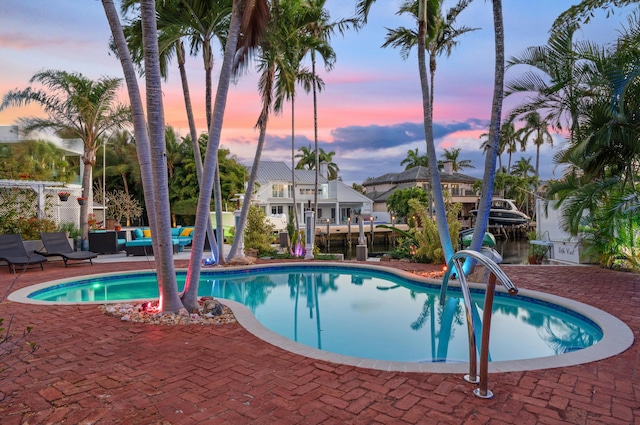 pool at dusk featuring an outdoor hangout area and a patio