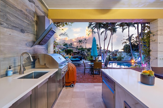 patio terrace at dusk with area for grilling, a grill, and an outdoor wet bar