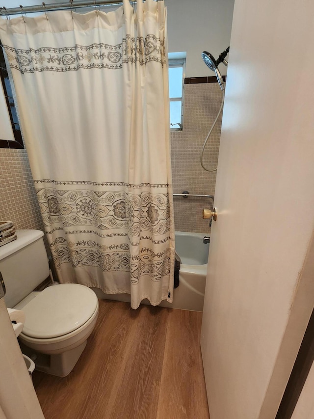 bathroom featuring hardwood / wood-style flooring, shower / bath combo, toilet, and tile walls