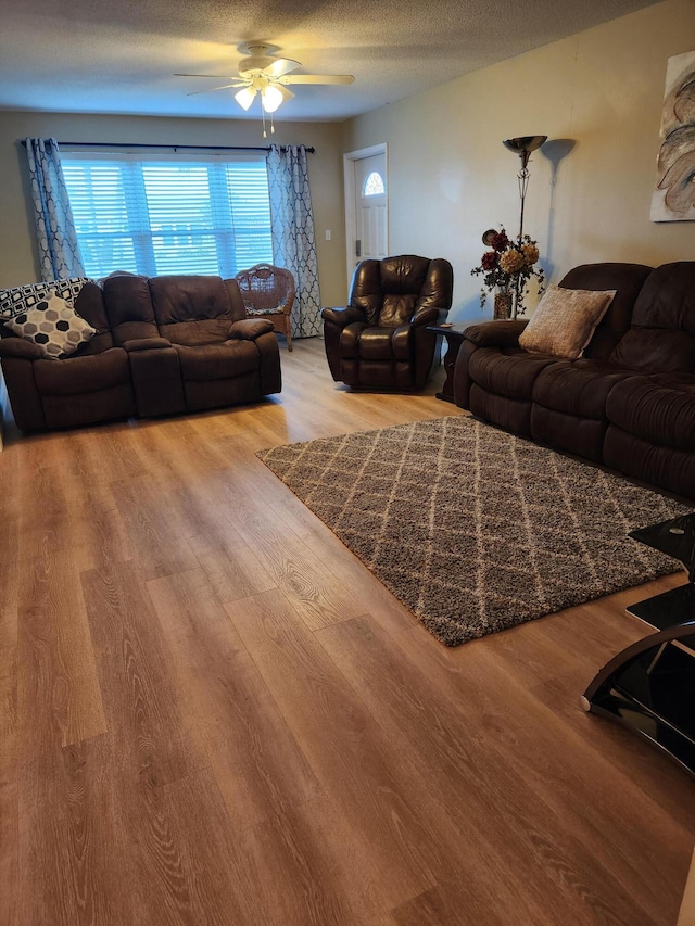 living room with hardwood / wood-style floors, a textured ceiling, and ceiling fan