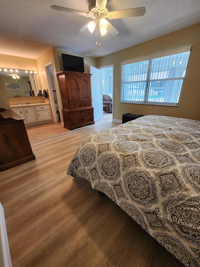 bedroom with a textured ceiling, light hardwood / wood-style floors, and ceiling fan