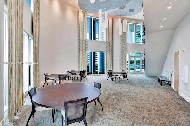 carpeted dining area with a healthy amount of sunlight and a towering ceiling