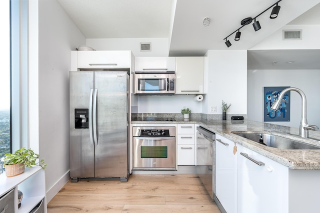 kitchen featuring sink, white cabinets, light hardwood / wood-style floors, and appliances with stainless steel finishes