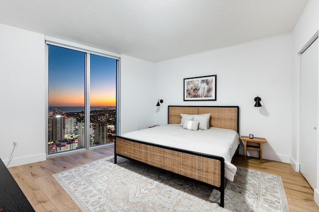 bedroom featuring a wall of windows, a textured ceiling, and hardwood / wood-style flooring