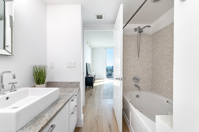 bathroom with vanity, wood-type flooring, and tiled shower / bath