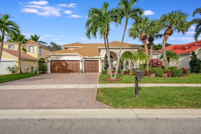 mediterranean / spanish house featuring a garage and a front lawn