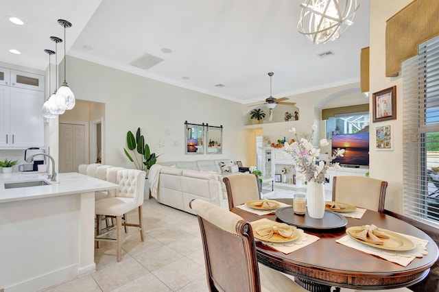 tiled dining area featuring sink, ceiling fan with notable chandelier, and ornamental molding