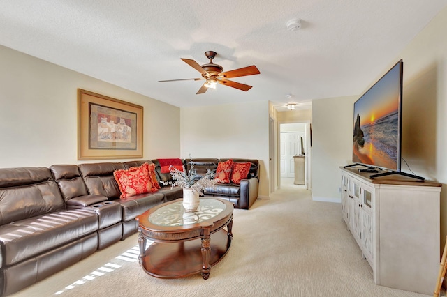 living room featuring ceiling fan, light colored carpet, and a textured ceiling