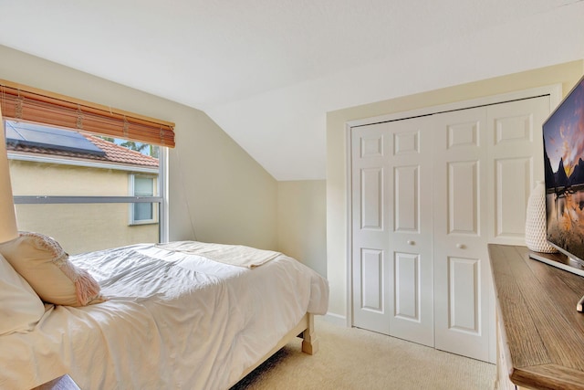 carpeted bedroom with a closet and lofted ceiling