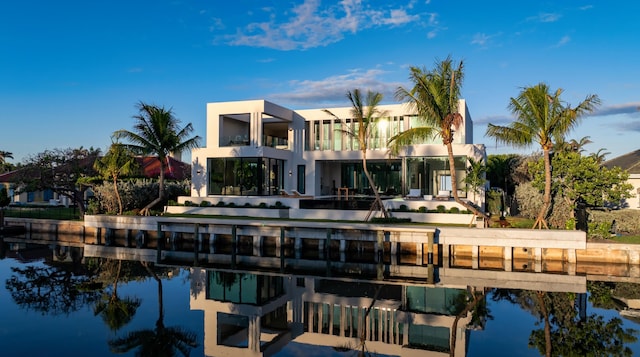 back of house featuring a water view, a balcony, and stucco siding