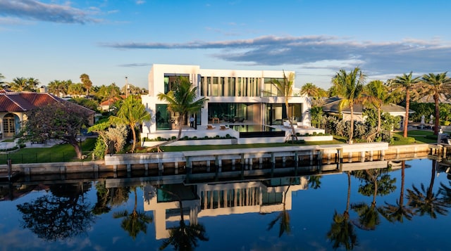 back of house with a water view and stucco siding