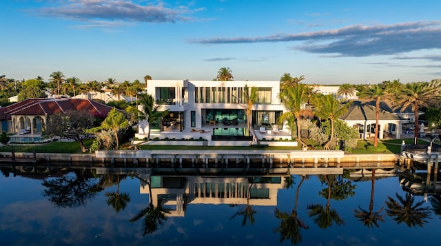 back of house featuring a water view, a balcony, and stucco siding