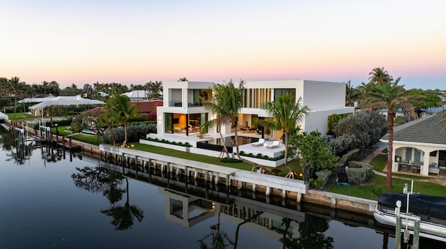 rear view of house featuring a balcony, a water view, a residential view, stucco siding, and a patio area