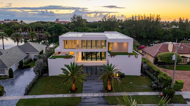 view of front of home with stucco siding, fence, and a yard