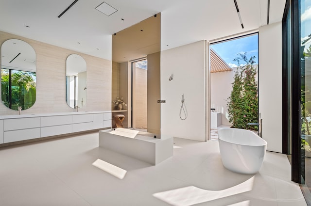 bathroom with a healthy amount of sunlight, floor to ceiling windows, a freestanding bath, and vanity