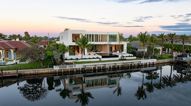 back of house with a yard, a water view, a balcony, and stucco siding