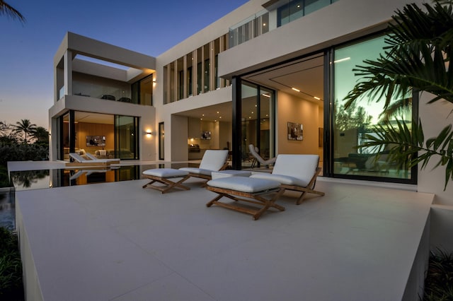 back of property at dusk with a patio area and stucco siding