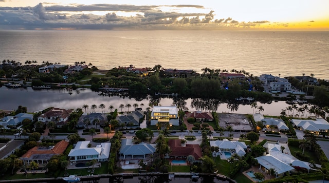 aerial view at dusk featuring a water view and a residential view