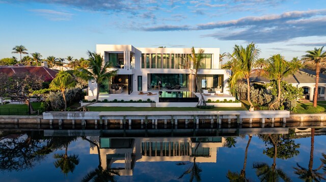 back of property featuring a water view, a balcony, and stucco siding