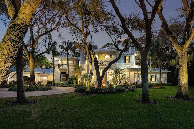 view of front of house featuring a balcony and a lawn