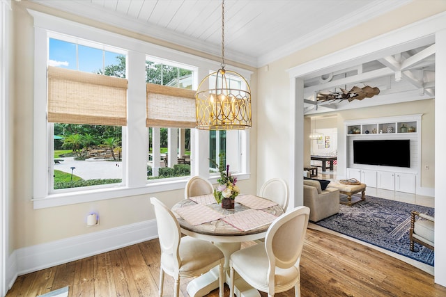 dining space with ornamental molding, plenty of natural light, wood-type flooring, and an inviting chandelier