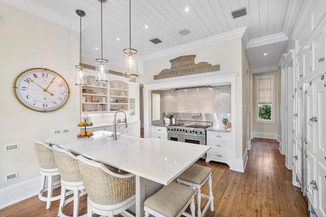 kitchen featuring crown molding, a breakfast bar area, hanging light fixtures, dark hardwood / wood-style floors, and white cabinets