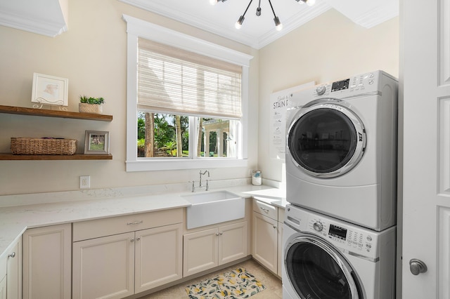 laundry room featuring cabinets, ornamental molding, stacked washer / drying machine, and sink