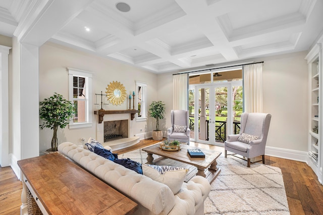 living room featuring french doors, a fireplace, light hardwood / wood-style floors, and beam ceiling