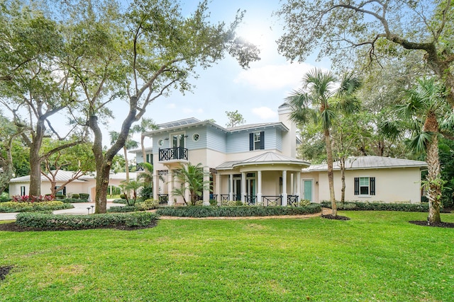 view of front of house with a balcony and a front lawn