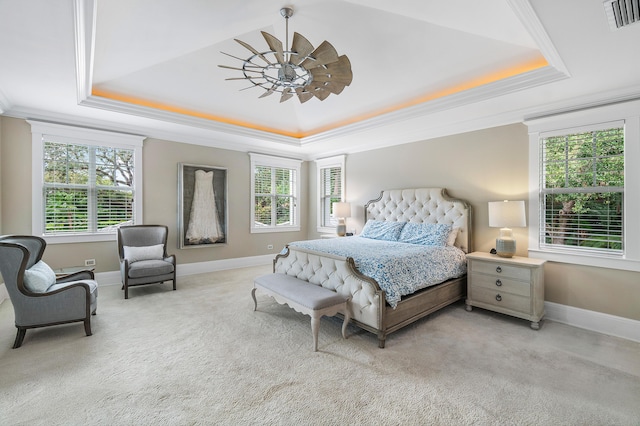 carpeted bedroom with a raised ceiling, ornamental molding, and ceiling fan