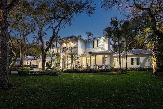 view of front of home featuring a balcony and a front lawn