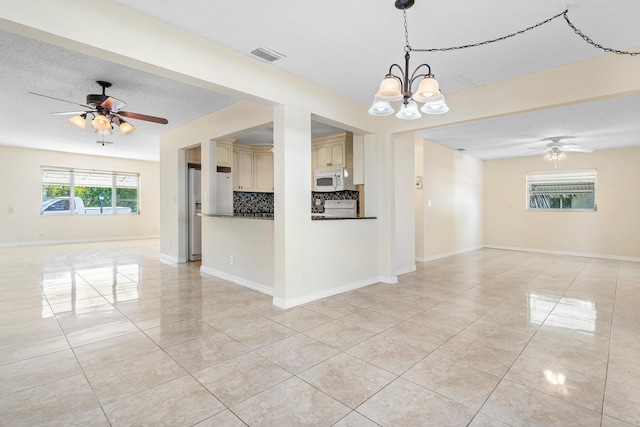 tiled empty room featuring ceiling fan with notable chandelier and a textured ceiling