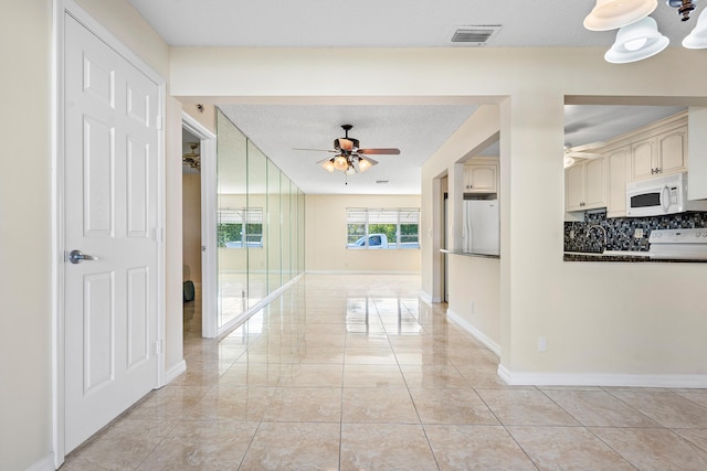 corridor with light tile patterned flooring and a textured ceiling