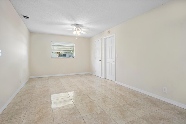 tiled empty room featuring ceiling fan and a textured ceiling