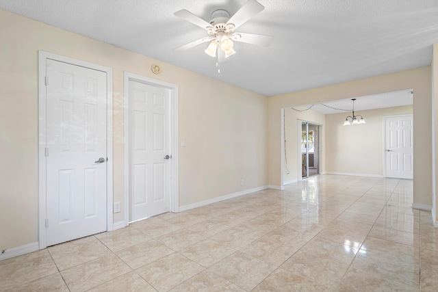 unfurnished room with a textured ceiling, ceiling fan with notable chandelier, and light tile patterned flooring