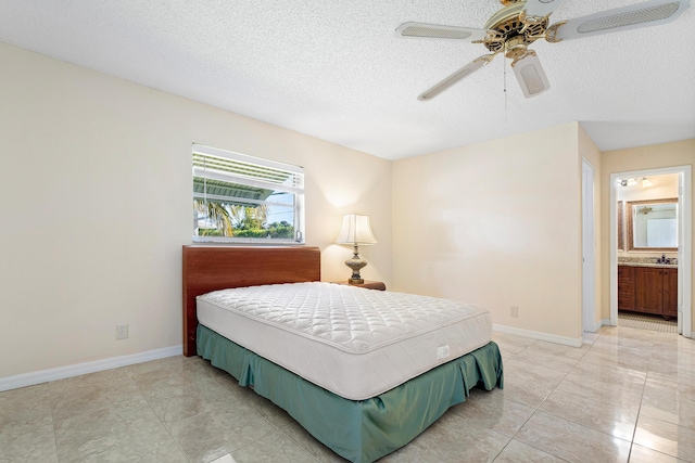 bedroom with ceiling fan, light tile patterned flooring, a textured ceiling, and connected bathroom