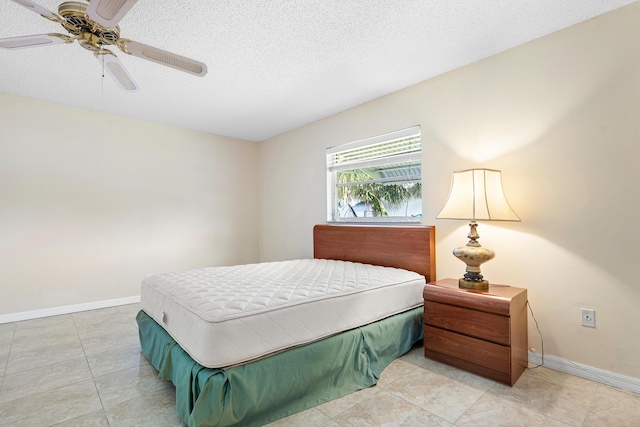 tiled bedroom featuring ceiling fan and a textured ceiling