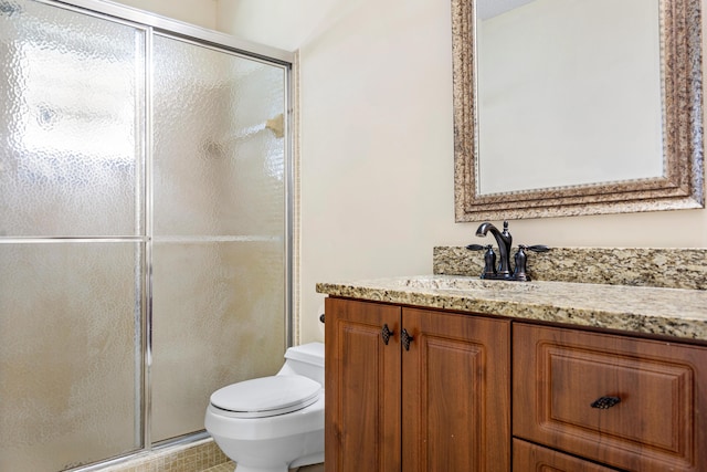 bathroom with tile patterned floors, vanity, an enclosed shower, and toilet